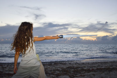 Woman standing at beach against sky