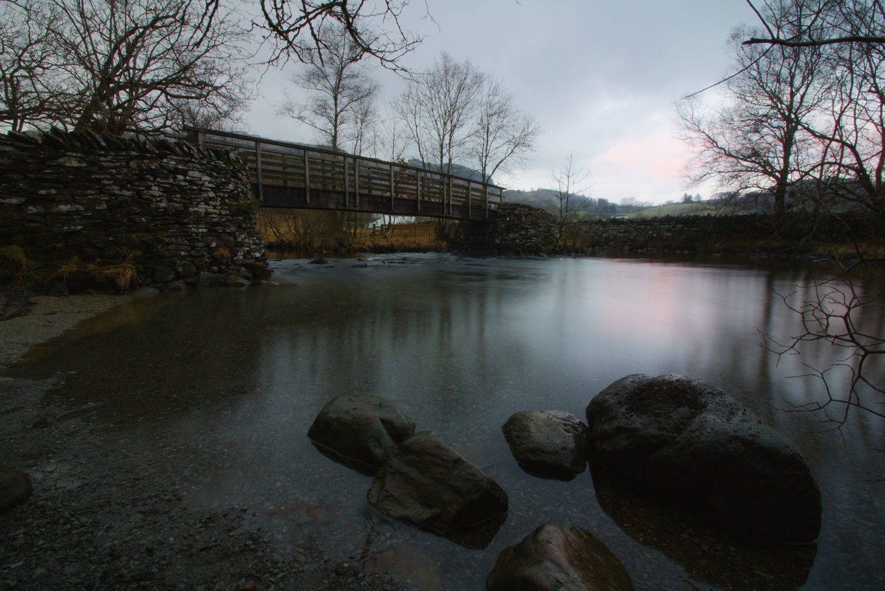 BRIDGE OVER RIVER AGAINST BARE TREES