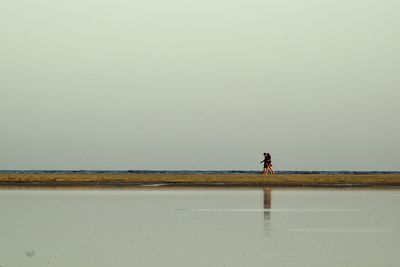 Man walking on beach against clear sky