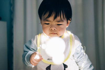 Cute boy playing with illuminated lighting equipment at home