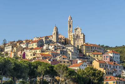 Buildings in city against clear blue sky