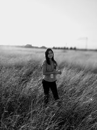 Portrait of girl standing on field against sky