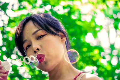 Close-up portrait of woman blowing bubbles