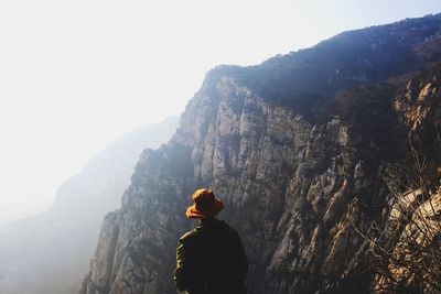 Rear view of man standing against mountains during foggy weather