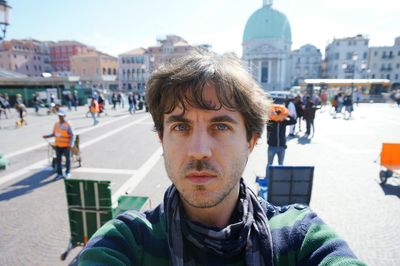 Portrait of handsome man standing at town square during sunny day