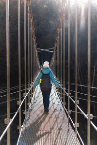 Rear view of woman walking on a suspension bridge sunshine day