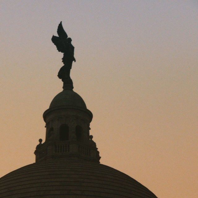 architecture, built structure, low angle view, building exterior, religion, place of worship, clear sky, spirituality, statue, sunset, copy space, sculpture, famous place, history, travel destinations, sky, art, art and craft, high section