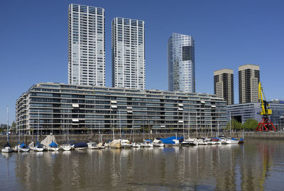 Boats in sea against clear blue sky