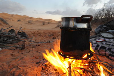 Close-up of bonfire on beach against sky during sunset