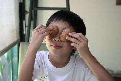 Close-up of playful boy holding food at home