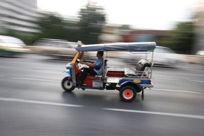 Blurred motion of man riding jinrikisha on road