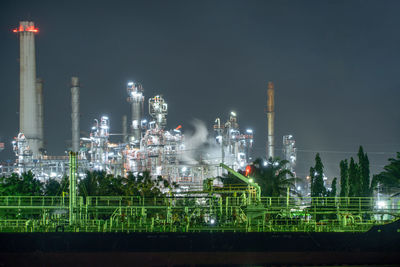 Illuminated factory against sky at night