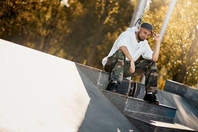 Full length of man with skateboard sitting on steps