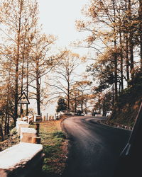 Road amidst bare trees against clear sky