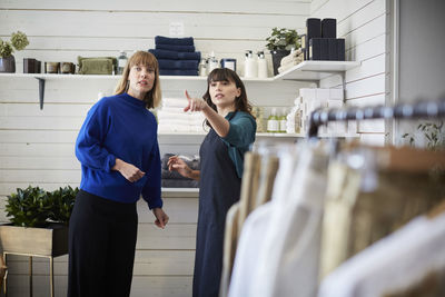 Female owner pointing and showing while communicating with customer at boutique