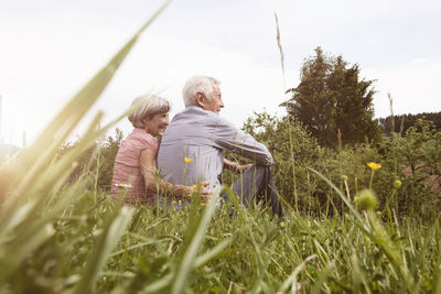 Relaxed senior couple sitting in meadow