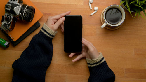 Midsection of woman holding coffee cup on table