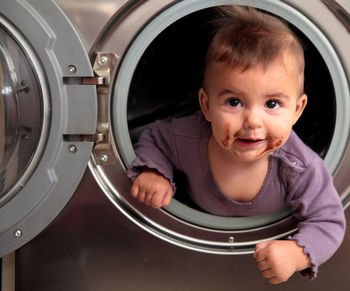 Close-up of little girl sitting in washing machine