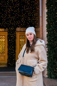 Portrait of smiling woman against christmas decoration during winter