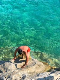 High angle view of man on rock by sea