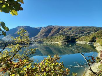 Scenic view of lake and mountains against clear blue sky