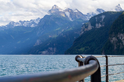 Scenic view of sea by mountains against sky