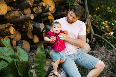 A happy father and his son are sitting on logs in the forest. happy fatherhood moments