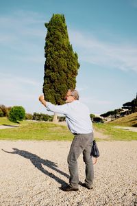 Optical illusion of senior man holding tree