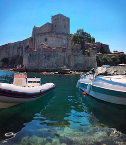 Boats moored in sea against blue sky