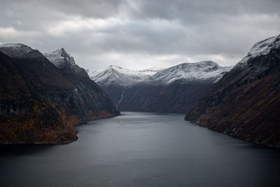 Scenic view of lake by snowcapped mountains against sky