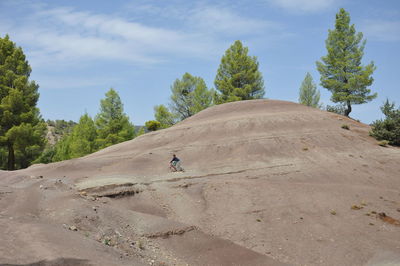 Man riding motorcycle on desert against sky