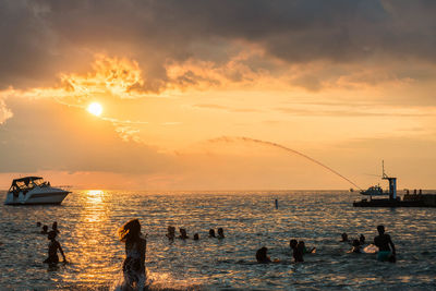 Silhouette people swimming in sea