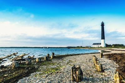 Lighthouse by sea against sky