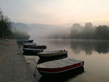 Boat moored on lake against sky during sunset