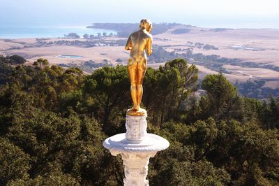 Statue of man standing on mountain against sky