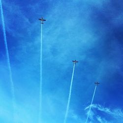 Low angle view of vapor trails against blue sky