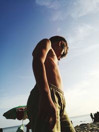Low angle view of shirtless boy standing at beach