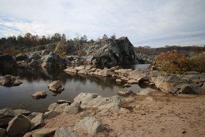 Rocks by river against sky