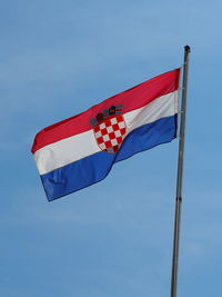 Low angle view of flag against blue sky