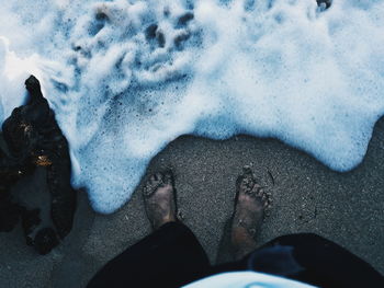 Low section of man standing on beach