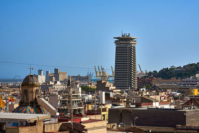 Buildings in city against clear blue sky