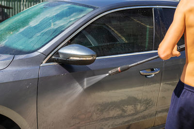 Midsection of man holding car