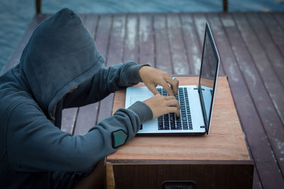 Midsection of man using mobile phone while sitting on table