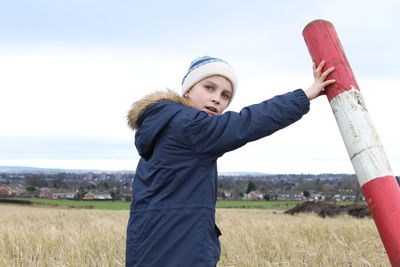 Portrait of boy standing on field against clear sky