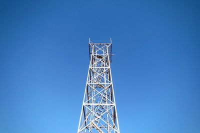 Low angle view of communications tower against blue sky