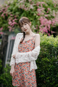 Young woman standing against plants