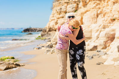 Two senior women are metting on a walk along a rocky beach