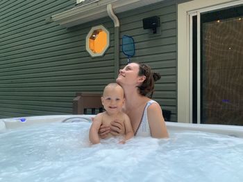 Cheerful mother in jacuzzi with kid