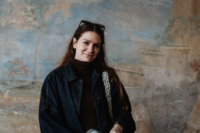 Portrait of young woman standing against wall