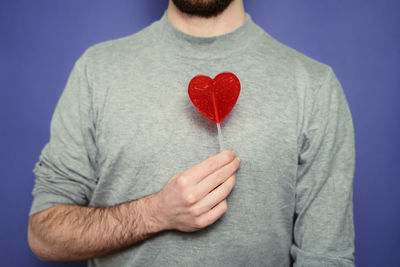 Midsection of man holding heart shape over white background